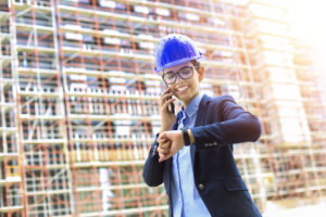 Doing things on time a woman with a construction hat talking on the phone and checking the time on her watch