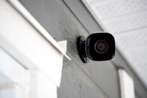 Black cctv outside building, home security system a black stick up camera on the house wall
