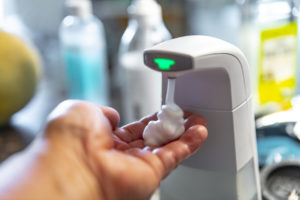a hand holding the soap coming out of the soap dispenser