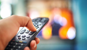 Watching tv POV a hand using a tv remote control