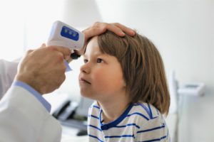 Cropped image of doctor measuring temperature of boy with infrared thermometer at hospital doctor measuring temperature of boy with infrared thermometer