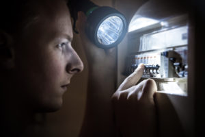 Man restoring power on circuit breaker after electricity outage a man holding the Energizer flashlight restoring power on circuit breaker